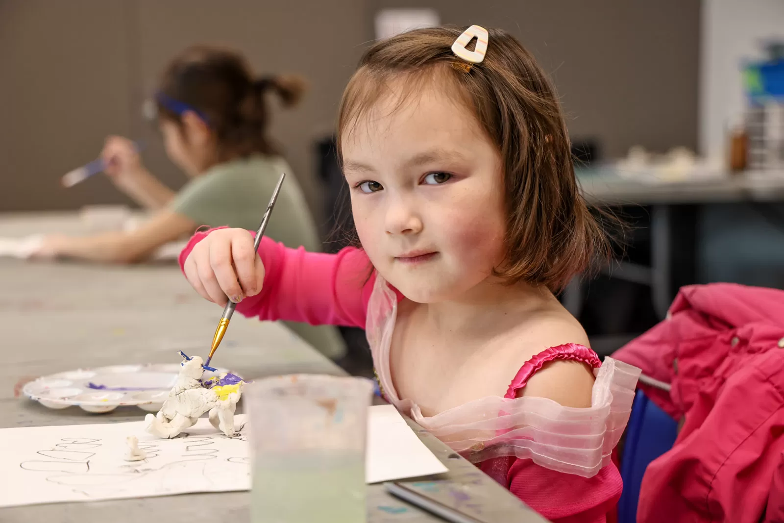 A child poses for a photo while painting