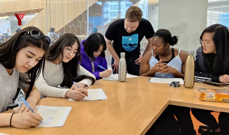 kids sitting around a table being tutored with Y logo in the top left corner