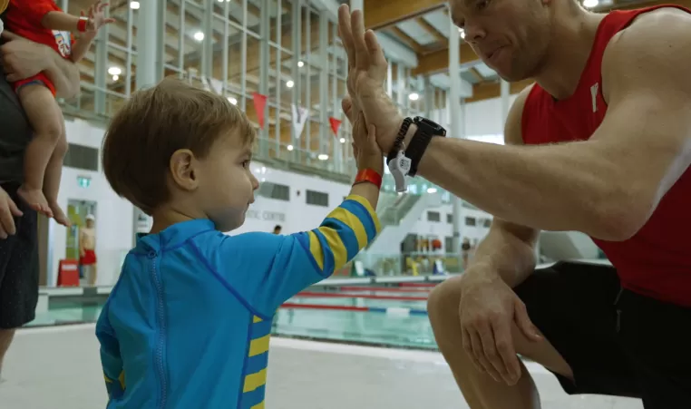 A YMCA Calgary lifeguard high-fives a young swimmer