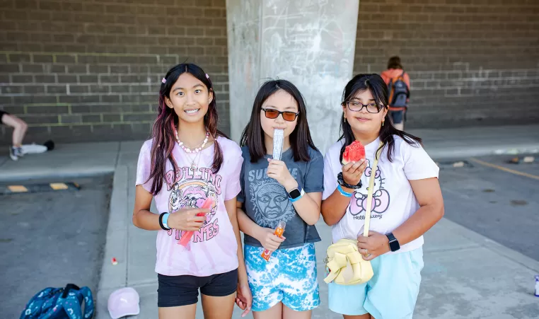 Three girls pose for a photo outside during a summer celebration