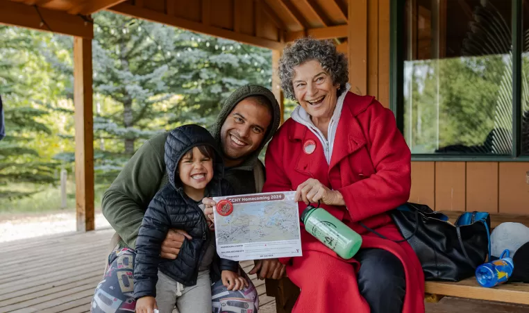 A family sit outside of Hector Lodge with their map of Camp Chief Hector Homecoming 2024