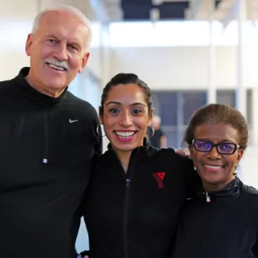 A group of three individuals stand next to each other, donning smiles and YMCA clothing