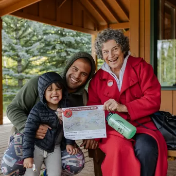 A family sit outside of Hector Lodge with their map of Camp Chief Hector Homecoming 2024